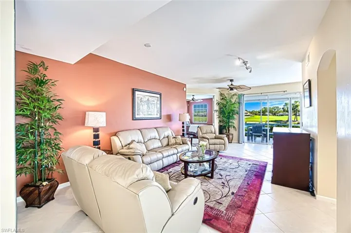 Living room featuring light tile patterned floors, arched walkways, baseboards, ceiling fan, and track lighting