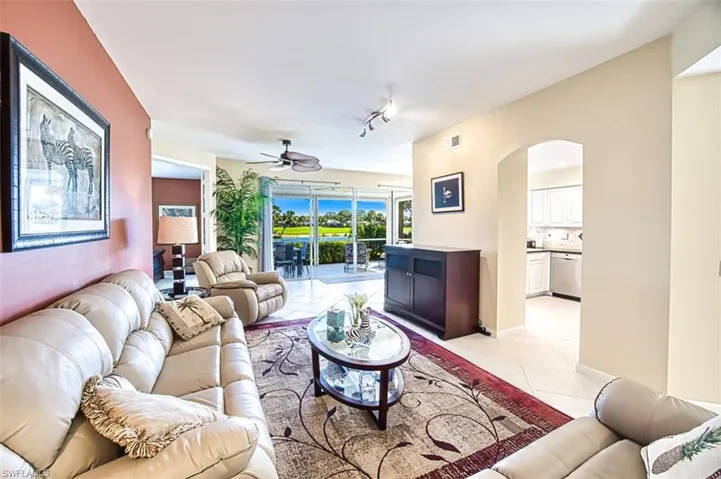 Living room with light tile patterned floors, arched walkways, a ceiling fan, visible vents, and track lighting