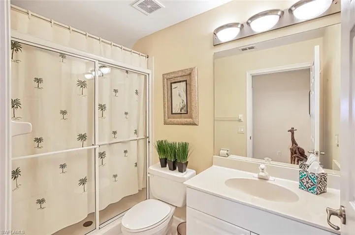Full bathroom featuring toilet, a shower stall, visible vents, and vanity