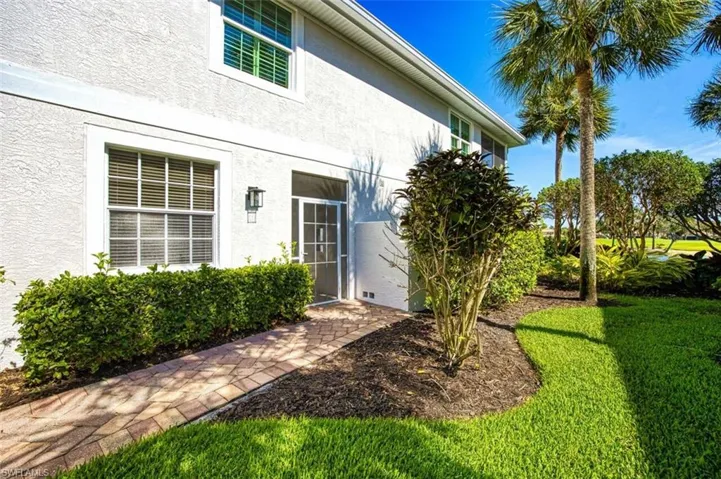 Doorway to property with a lawn and stucco siding