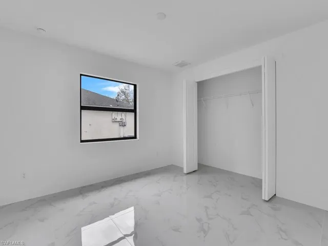 Unfurnished bedroom featuring marble finish floor and a closet
