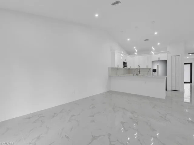 Unfurnished living room with visible vents, marble finish floor, recessed lighting, baseboards, and lofted ceiling