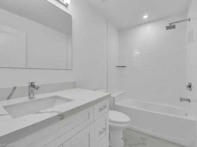 Bathroom with vanity, recessed lighting, toilet, marble finish floor, and shower / bathtub combination