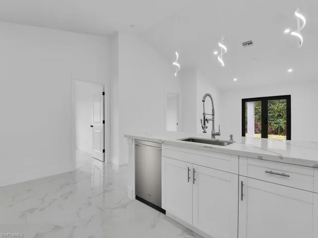 Kitchen with white cabinetry, a sink, french doors, stainless steel dishwasher, and marble finish floor