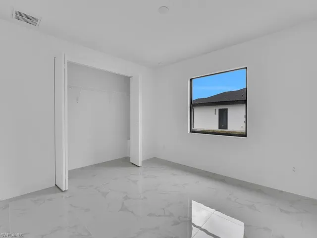 Unfurnished bedroom with visible vents, marble finish floor, and a closet