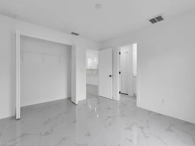 Unfurnished bedroom with a closet, baseboards, visible vents, and marble finish floor