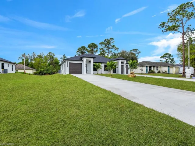 View of front of home with a front yard, a garage, driveway, and roof with shingles