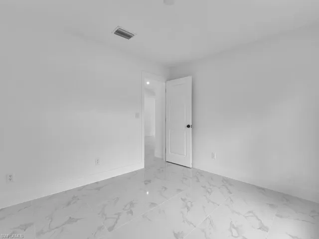 Empty room with visible vents, marble finish floor, and baseboards
