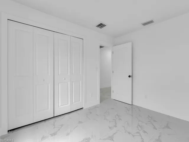 Unfurnished bedroom featuring a closet, visible vents, marble finish floor, and baseboards