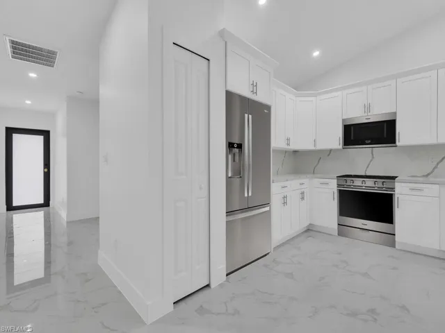 Kitchen with visible vents, marble finish floor, stainless steel appliances, and decorative backsplash