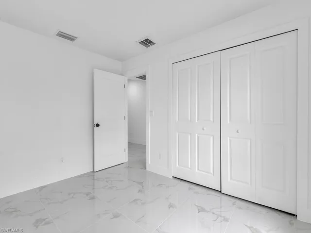 Unfurnished bedroom featuring visible vents, baseboards, marble finish floor, and a closet