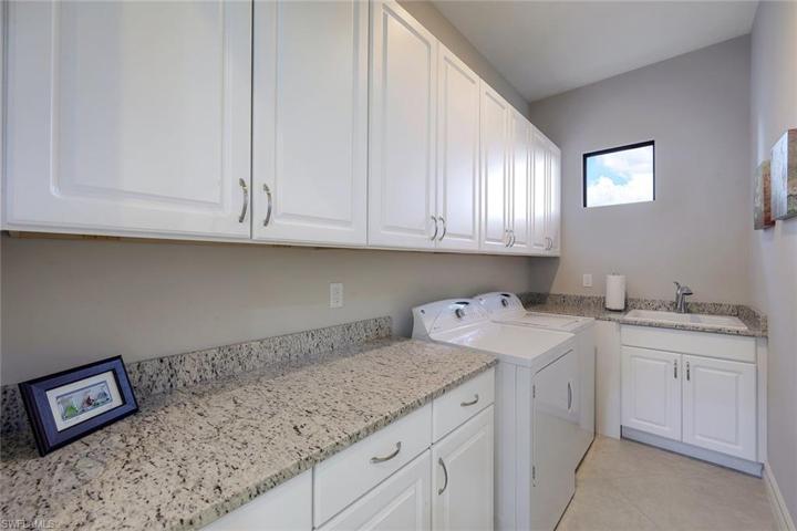 Laundry room with ample storage, closet, full size washer and dryer, & a utility sink.