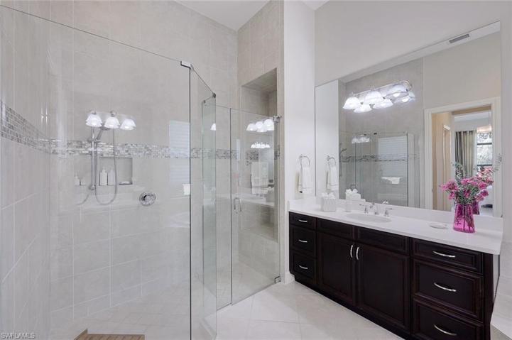 Primary bath walk in showing with frameless glass surround and sitting area in the shower.