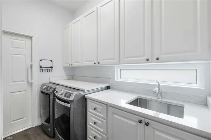 Washroom featuring independent washer and dryer, cabinet space, and wood-style floors. Note: Dated glass bricks replaced with beautiful Impact Glass.