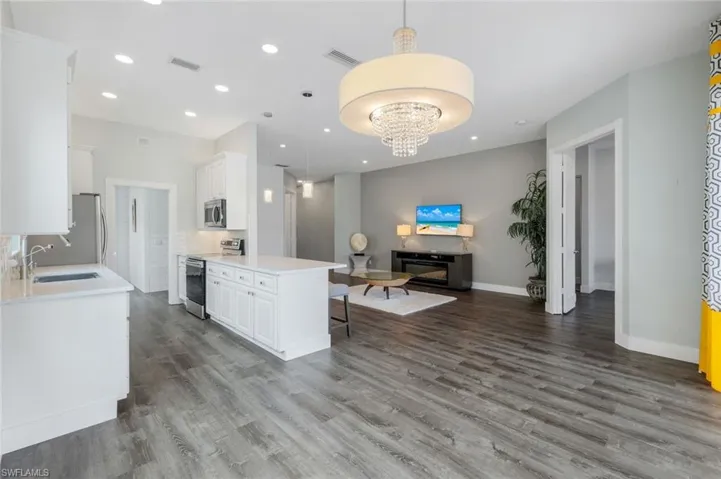 Kitchen with a sink, stainless steel appliances, open floor plan, wood finished floors, and recessed lighting