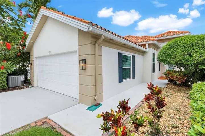 View of side of property with central AC, stucco siding, and a tile roof
