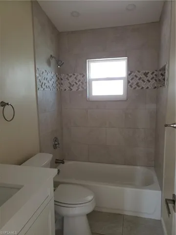 Bathroom with vanity, shower / tub combination, and light tile patterned floors