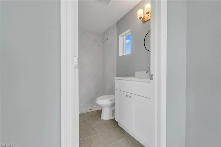 Full bath with toilet, tile patterned flooring, tiled shower, and vanity