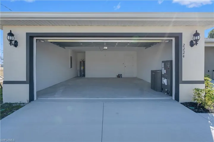 Garage featuring driveway, electric water heater, and electric panel