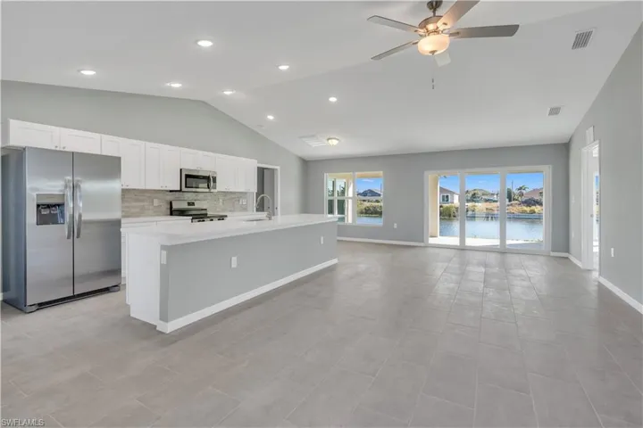 Kitchen featuring stainless steel appliances, light countertops, visible vents, open floor plan, and a sink