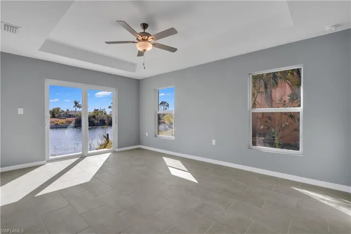 Spare room featuring ceiling fan, visible vents, baseboards, tile patterned floors, and a raised ceiling