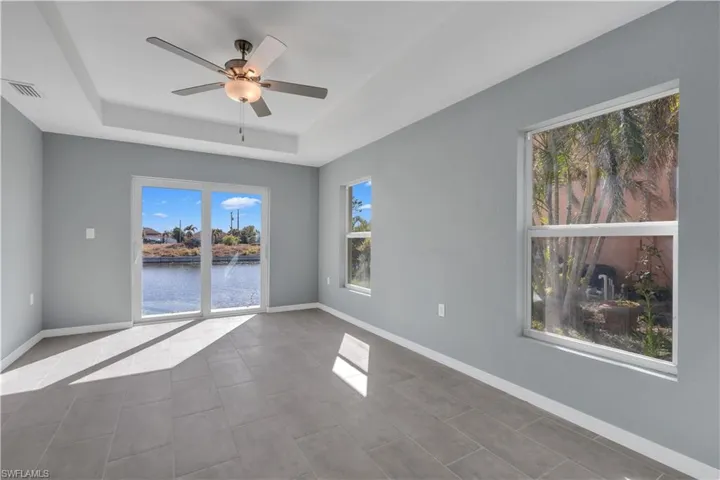 Spare room with a raised ceiling, visible vents, ceiling fan, tile patterned flooring, and baseboards