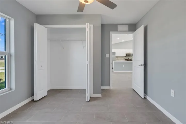 Unfurnished bedroom with freestanding refrigerator, a closet, visible vents, and baseboards