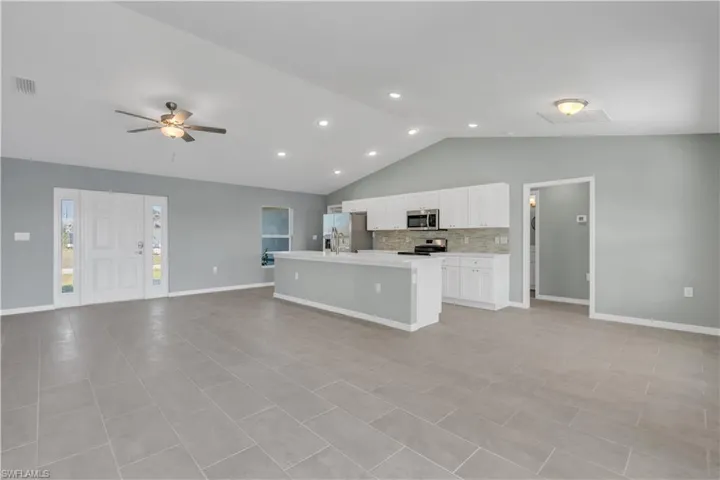 Kitchen featuring visible vents, decorative backsplash, appliances with stainless steel finishes, open floor plan, and light countertops