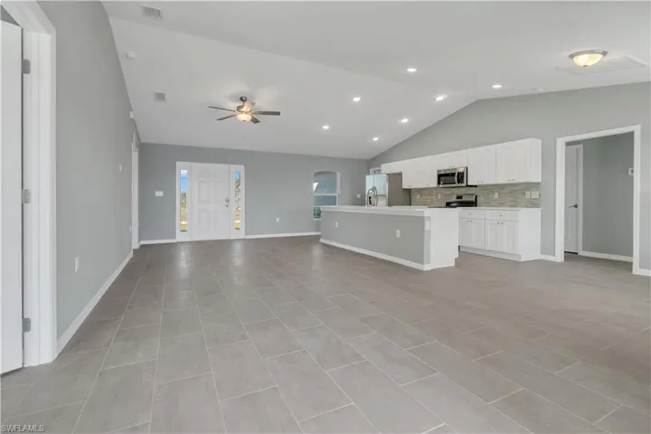 Kitchen featuring stainless steel appliances, visible vents, white cabinets, open floor plan, and a center island with sink