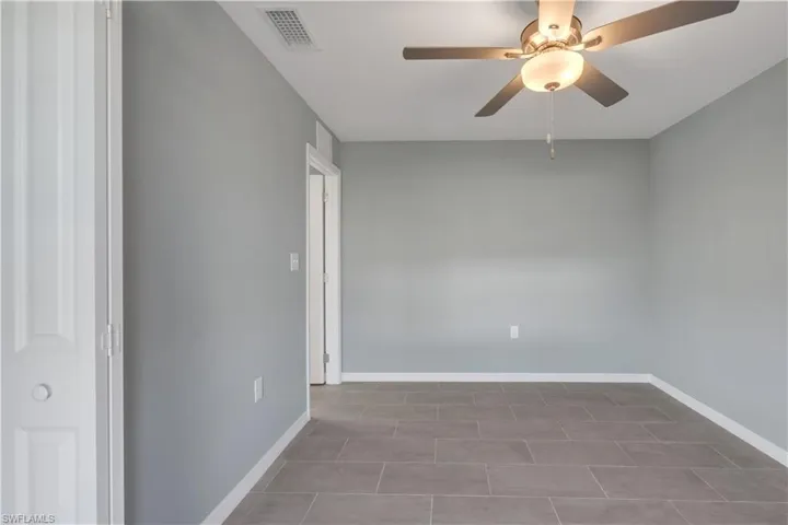 Unfurnished room with a ceiling fan, visible vents, and baseboards