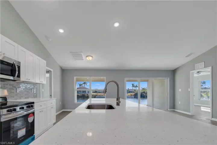 Kitchen with tasteful backsplash, visible vents, appliances with stainless steel finishes, a sink, and light stone countertops