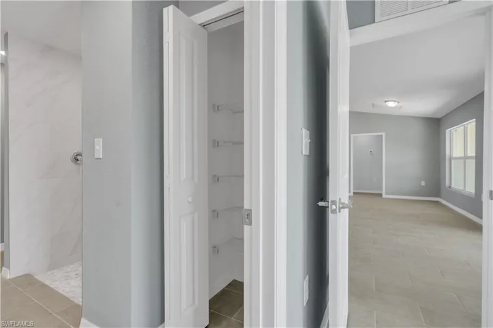 Bathroom with tile patterned flooring, visible vents, baseboards, and walk in shower