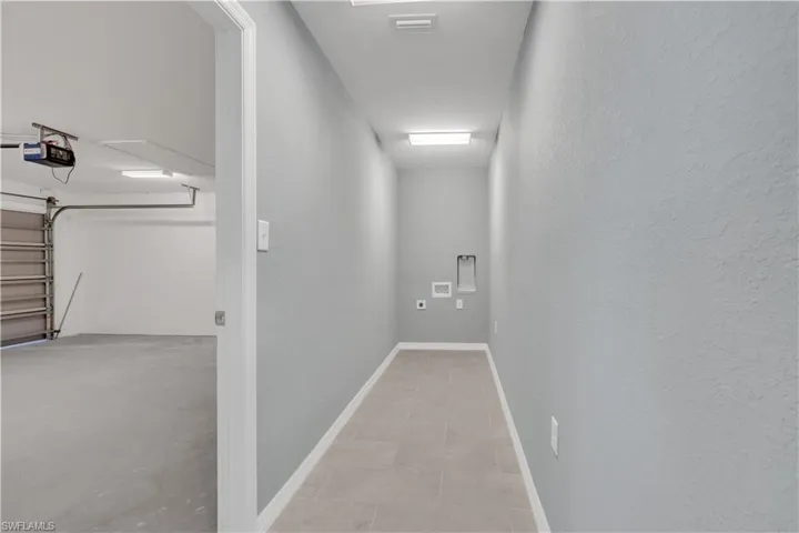 Hallway with a textured wall, visible vents, and baseboards