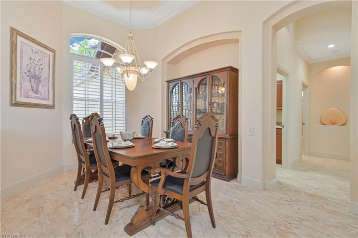 Dining area featuring marble-finish flooring, an arched entryway, and crown molding