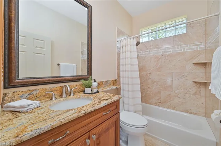 Bathroom vanity featuring a polished stone countertop with an undermount sink and brushed nickel faucet