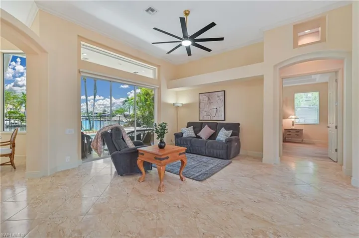Living area featuring high ceilings, large format tile flooring, a modern ceiling fan, and sliding glass doors opening to an outdoor space with a pool
