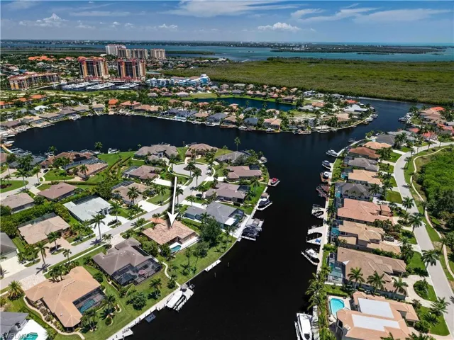 Waterfront property featuring a private boat dock, pool, and mature palm trees