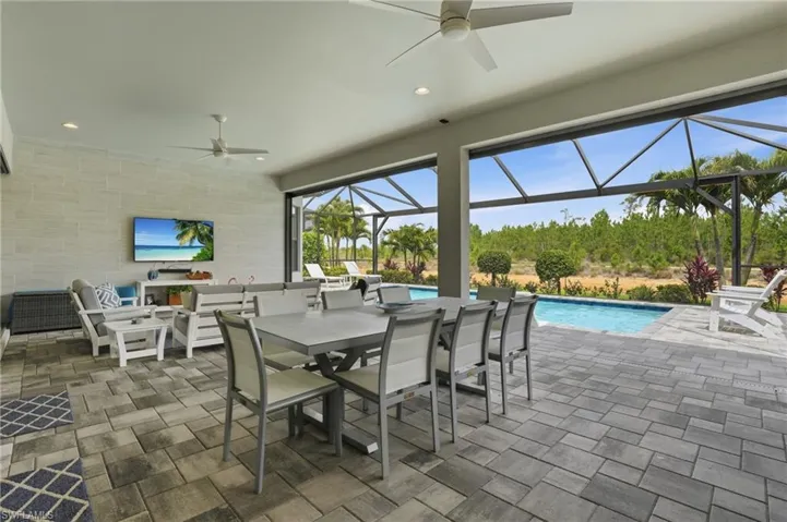 Screened outdoor living area featuring a paved patio and a swimming pool
