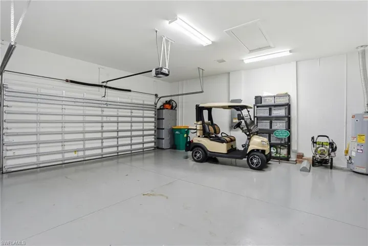 Spacious garage featuring a light gray epoxy floor, automatic overhead door, fluorescent lighting, and a ceiling-mounted access panel