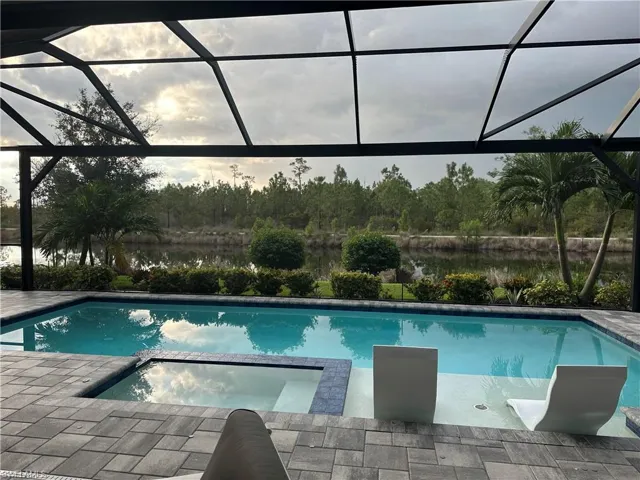 Screened outdoor living area featuring a rectangular pool with an integrated spa