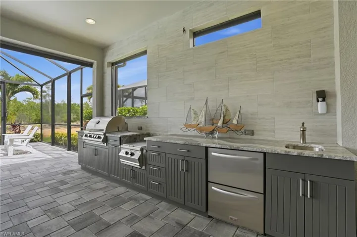 Outdoor kitchen featuring an integrated grill, side burner, and undercounter refrigeration
