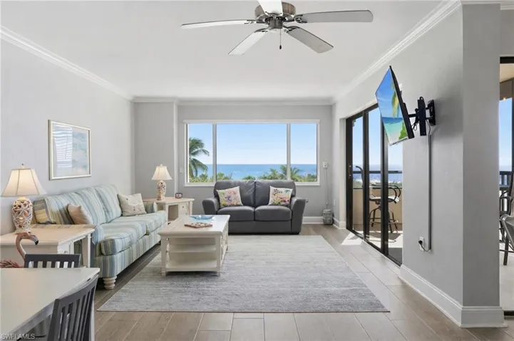 Living room with a ceiling fan, light wood-style flooring, and crown molding