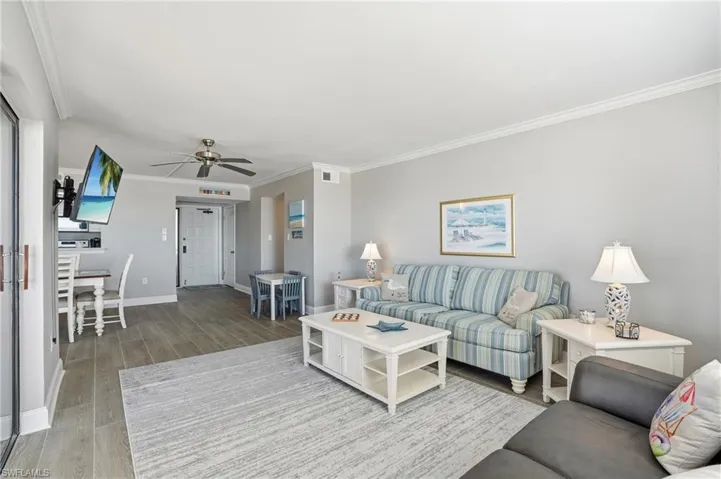 Living area with light wood-style flooring, ornamental molding, and a ceiling fan
