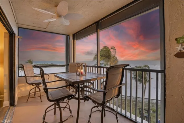 Sunroom / solarium with a water view, a textured wall, expansive windows, and a textured ceiling