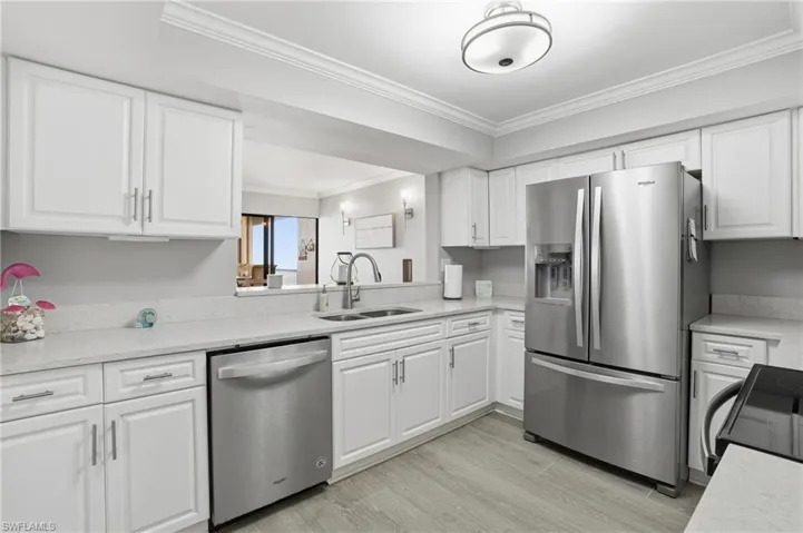 Kitchen with stainless steel appliances, white cabinetry, and crown molding