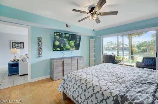 Light wood-finish flooring, ceiling fan with integrated lighting, built-in shelving, and sliding glass doors