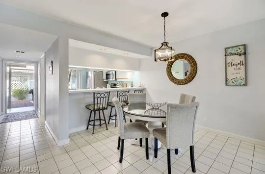 White tiled flooring, recessed lighting, and a pass-through bar with overhead lighting
