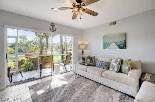 Sliding glass doors opening to an enclosed patio, wood-finish ceiling fan, and tile flooring