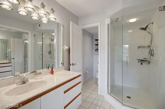 Double vanity with a single basin, surface-mounted lighting fixture, framed mirror, and glass-enclosed shower