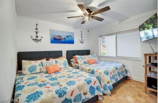 Room featuring wood-finish flooring, a ceiling fan with integrated lighting, and a window with roller shades
